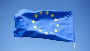 Прапор ЄС поряд із символічним зображенням санкційного пакета